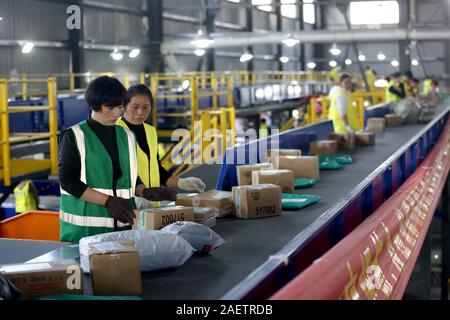 Lavoratori a EMS (Express Mail Service) centro logistico di riordinare i pacchi come doppio 11 picchi di erogazione in Huai'an City, est della Cina di provincia dello Jiangsu Foto Stock