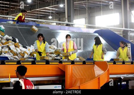 Lavoratori a EMS (Express Mail Service) centro logistico di riordinare i pacchi come doppio 11 picchi di erogazione in Huai'an City, est della Cina di provincia dello Jiangsu Foto Stock