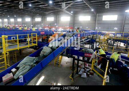 Lavoratori a EMS (Express Mail Service) centro logistico di riordinare i pacchi come doppio 11 picchi di erogazione in Huai'an City, est della Cina di provincia dello Jiangsu Foto Stock