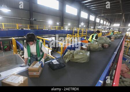 Lavoratori a EMS (Express Mail Service) centro logistico di riordinare i pacchi come doppio 11 picchi di erogazione in Huai'an City, est della Cina di provincia dello Jiangsu Foto Stock