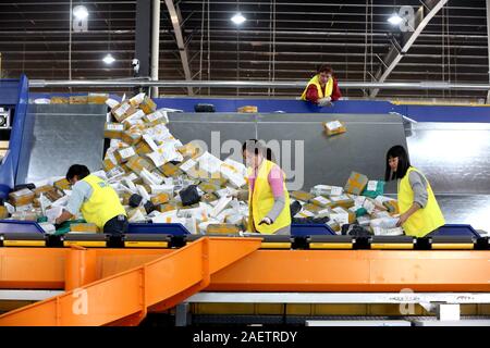 Lavoratori a EMS (Express Mail Service) centro logistico di riordinare i pacchi come doppio 11 picchi di erogazione in Huai'an City, est della Cina di provincia dello Jiangsu Foto Stock