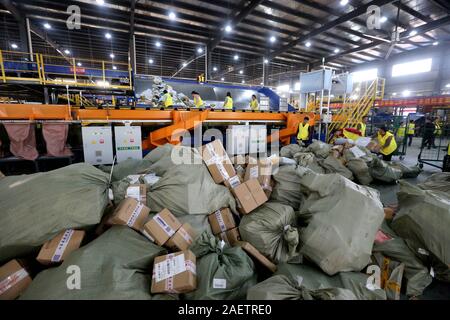 Lavoratori a EMS (Express Mail Service) centro logistico di riordinare i pacchi come doppio 11 picchi di erogazione in Huai'an City, est della Cina di provincia dello Jiangsu Foto Stock