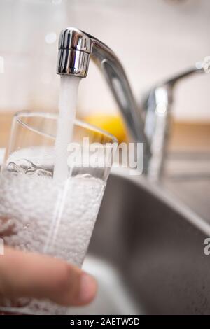 Duesseldorf, Germania. Decimo Dec, 2019. Illustrazione - un uomo tiene un bicchiere sotto l'acqua corrente. Il Bündnis 90/Die Grünen i commenti del gruppo sulla base dei risultati di un'inchiesta sull'acqua nel NRW. Una delle questioni in gioco è lo sviluppo di acqua per uso domestico di consumo. Credito: Marius Becker/dpa/Alamy Live News Foto Stock