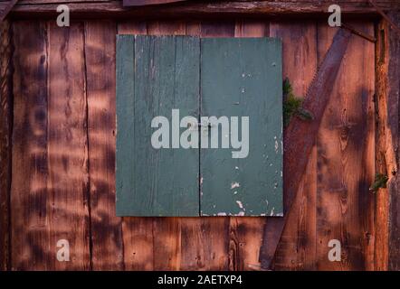 Sfondo di legno di un vecchio muro in legno con un weathered chiusa la finestra verde e rusty vide così come rami d abete decorativamente montato in Baviera Foto Stock