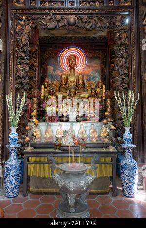 Un altare comprese offerte e un dorato statua buddista all'interno di una pagoda nel Vietnam del sud Foto Stock