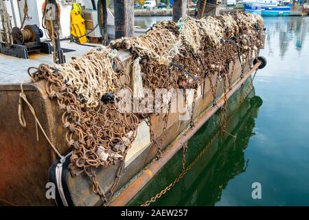 Il lato posteriore di una barca da pesca nel porto, che mostra le reti e le catene Foto Stock