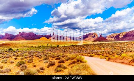 La strada sterrata che costeggia la pietra arenaria rossa Buttes e pinnacoli in semi deserto paesaggio della valle della divinità del Parco Statale di Mexican Hat, Utah Foto Stock