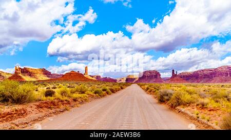 La strada sterrata che costeggia la pietra arenaria rossa Buttes e pinnacoli in semi deserto paesaggio della valle della divinità del Parco Statale di Mexican Hat, Utah Foto Stock