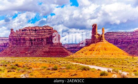 La strada sterrata che costeggia la pietra arenaria rossa Buttes e pinnacoli in semi deserto paesaggio della valle della divinità del Parco Statale di Mexican Hat, Utah Foto Stock