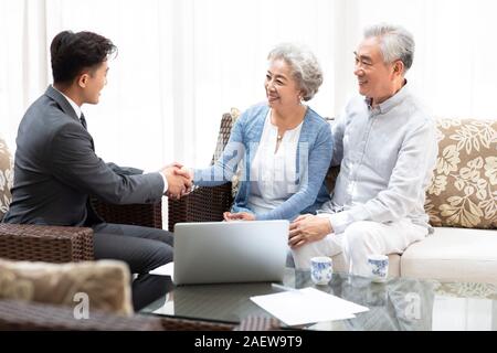 Felice coppia senior stringono le mani con il consulente finanziario Foto Stock