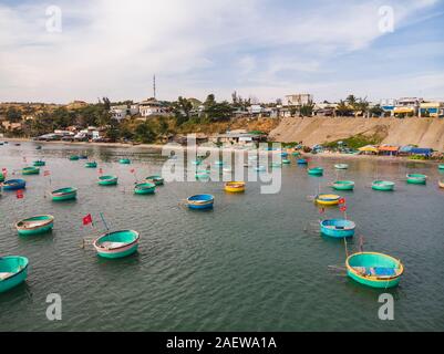 Pescatore cestello di pesca sulle imbarcazioni del Vietnamita villaggio di pescatori e colorati di pesca tradizionale imbarcazione attraccata Mui Ne, Vietnam. Vista dall'alto. Vista aerea Foto Stock