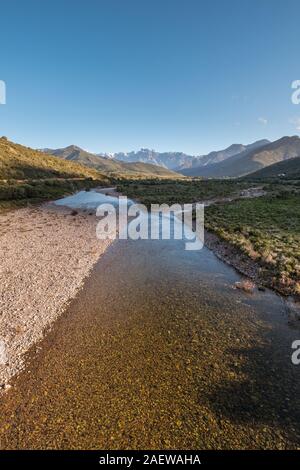 Le acque cristalline del fiume di fango vicino a Galeria in Corsica con la neve montagna ricoperte di Paglia Orba a distanza Foto Stock