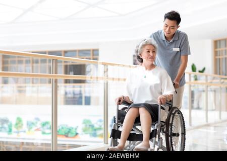 Assistente infermieristica avendo cura di senior donna in sedia a rotelle Foto Stock