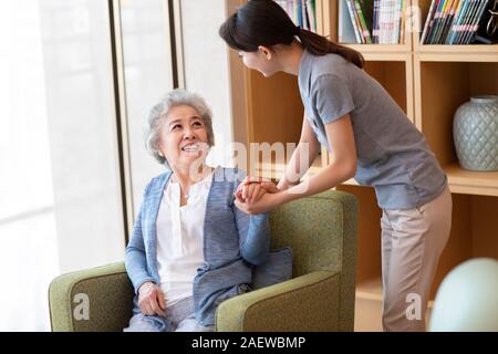 Assistente infermieristica prendendo con senior donna nella casa di cura Foto Stock