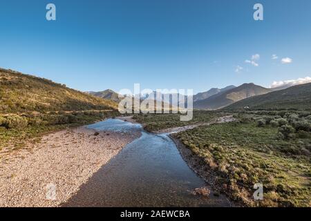 Le acque cristalline del fiume di fango vicino a Galeria in Corsica con la neve montagna ricoperte di Paglia Orba a distanza Foto Stock