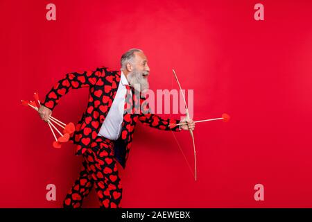 Foto del profilo di funky pazzo uomo più anziano guy cupido vedere la bella coppia andando a sparare amore bow freccia cuori indossare tuta modello di maglietta pantaloni cravatta rossa isolato Foto Stock