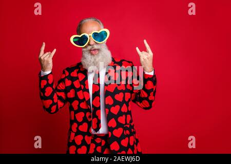 Foto di funky uomo più anziano amour cupido ruolo del carattere che mostra le corna dita eccitato emozioni usura sun specs cuori pattern costume tuta shirt tie Foto Stock