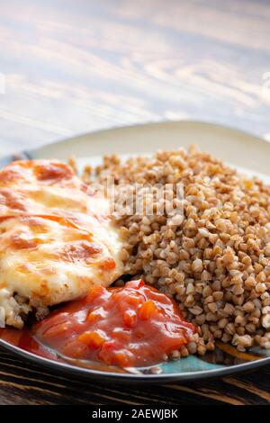 Pollo arrosto, il grano saraceno e verdure sulla piastra di sfondo di legno Foto Stock