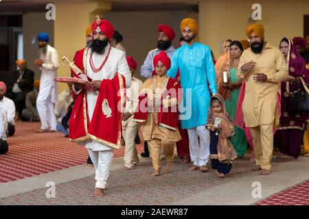 Un Sikh lo sposo in abito tradizionale entra in un tempio con la sua famiglia per la sua cerimonia nuziale. In South Richmond Hill, Queens, a New York. Foto Stock