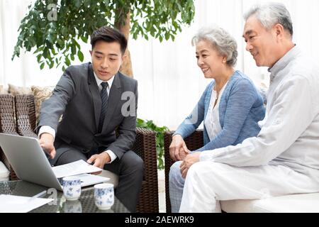 Felice coppia senior a parlare con il consulente finanziario in salotto Foto Stock