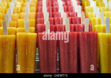 Naturali freschi di Puro succo di frutta aromatizzato ghiaccioli su bastoni di legno per la vendita in un contatore di freezer - gelato - ice popsicles - ice pops - aromi Foto Stock