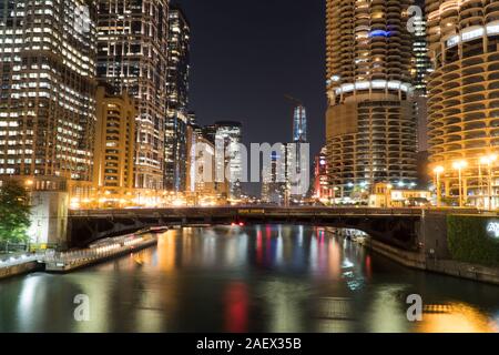 Notte tempo esterno che istituisce shot affacciato sul fiume Chicago zona anteriore con skyline illuminato nel cielo scuro che si riflette sull'acqua nella bellissima scen Foto Stock