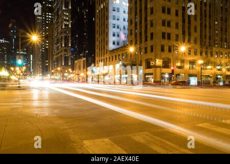 Tempo di notte lunga esposizione della trafficata strada urbana modo guidando attraverso città urbana area grattacieli del passato il centro con percorsi di luce di attraversamento di automobili si intersecano Foto Stock