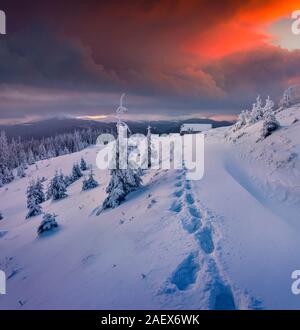 Mistico tramonto invernale in montagna. Vecchio ranch dopo la nevicata nel Carpahians, Ucraina, l'Europa. Foto Stock