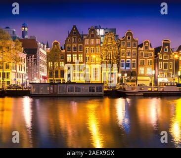 Splendida e tranquilla vista notturna della città di Amsterdam. Notte tempo illuminazioni di edifici con riflessioni su acqua e barche nel canale. Foto Stock