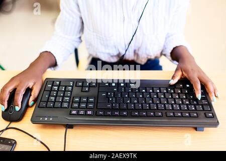 Donna africana le mani sulla tastiera nera e la tavola di legno. Foto Stock