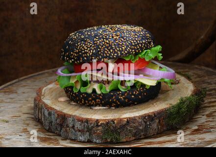 Burger di nero su uno sfondo di legno Foto Stock