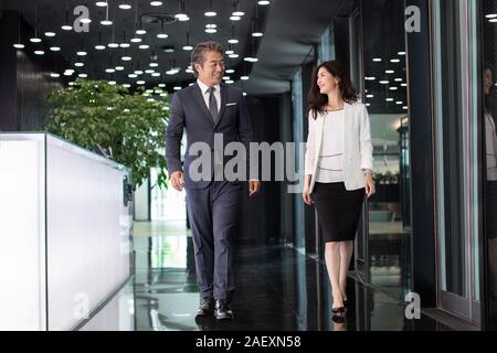 Due business di successo la gente camminare e parlare in lobby Foto Stock