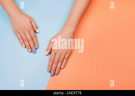 Manicure nei colori più alla moda: Corallo, Oro rosa e blu su sfondo colorato. Piatto stile di laici. Foto Stock