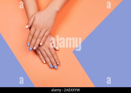 Manicure nei colori più alla moda: Corallo, Oro rosa e blu su sfondo colorato. Piatto stile di laici. Foto Stock