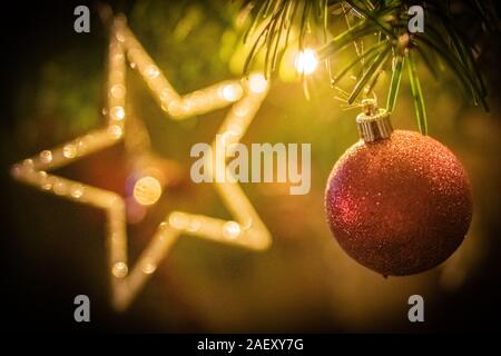 Albero di Natale decorato da vicino con glittery ninnolo, stringhe di luce e sfocata star Foto Stock