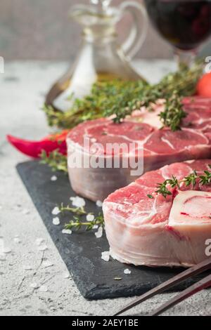 Freschi Stinco di vitello fette di carne di manzo per osso buco per la cottura sul tagliere con ingredienti e condimenti timo, pepe, sale. Foto Stock