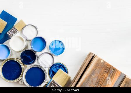 Preparazione per il restauro della scatola di legno con una spazzola e aprire le lattine di vernice blu Foto Stock