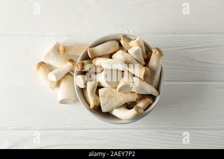 Eringi fresco di funghi in ciotola di legno bianco sfondo, vista dall'alto Foto Stock