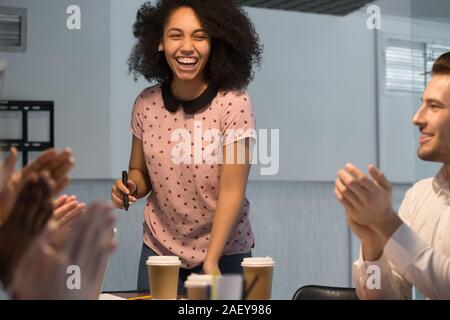 Diversi dipendenti applaudire ringraziando felice femmina nero presenter Foto Stock