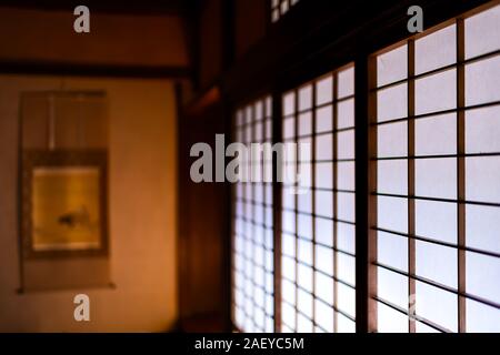 White porte scorrevoli di carta shoji chiusa in casa tradizionale giapponese o ryokan pattern e sfocata sullo sfondo di un tokonoma scorrere Foto Stock