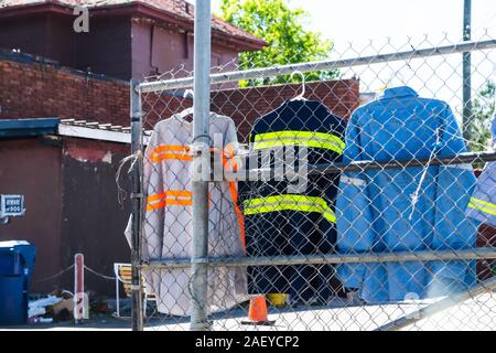 Complesso industriale esterno nel centro di Atlanta, Georgia città con lavoratori blu uniformi giacche appeso alla recinzione Foto Stock