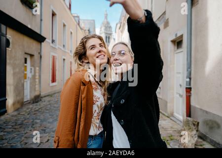 Giovani donne tenendo selfie in una tipica cittadina francese della strada Foto Stock