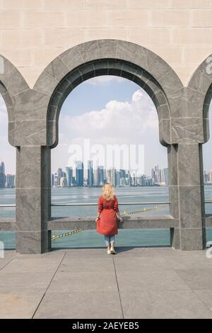 Vista posteriore della donna bionda in piedi e guardando il mare di Doha Foto Stock