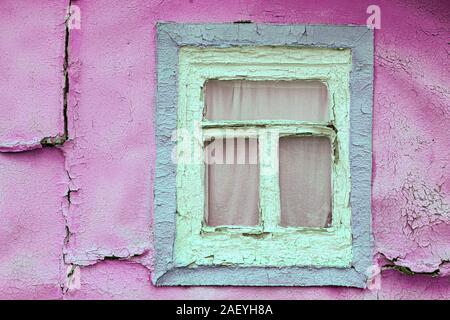 Vintage in legno rustico sul telaio di una finestra. Vecchi rosa pareti scrostate casa cottage. Foto Stock