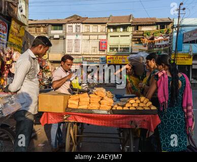 Una colorata scena di mercato dalla città vecchia con un venditore di strada che vende biscotti dal suo carrello stradale alle donne che li acquistano. Foto Stock