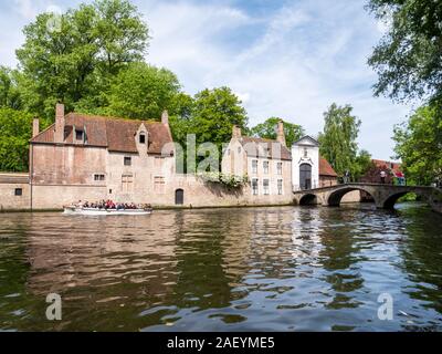 Barca con persone, ponte sul canal grande e la porta d ingresso al Begijnhof, beghinaggio, nel centro storico di Bruges, Belgio Foto Stock