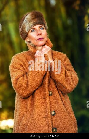 Donna bionda nel suo 40s passeggiate nel parco e godersi il sole autunnale Foto Stock