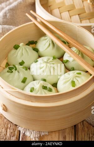 Fresh baozi in bambù sistema di cottura a vapore sul cinese cibo asiatico closeup sul piano verticale. Foto Stock