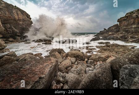 Vista di un wild cove con numerose rocce, e l'impatto delle onde sugli scogli in un mare mosso che mostra la furia dell'oceano. Scenario naturale, fre Foto Stock