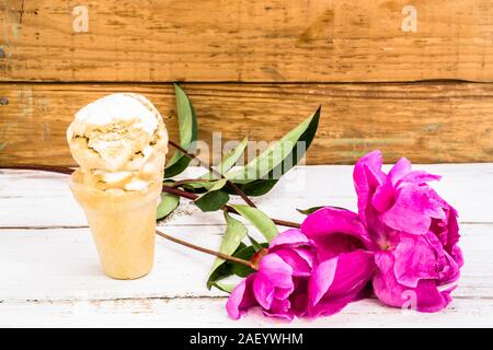 Cucchiaio di gelato in un cono di cialda su sfondo di legno Foto Stock